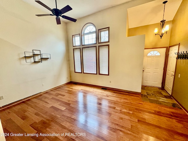 entrance foyer with a high ceiling, ceiling fan with notable chandelier, and hardwood / wood-style flooring