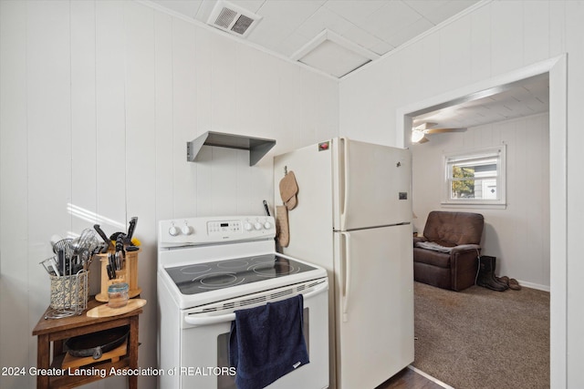 kitchen with white appliances, wood walls, ceiling fan, dark carpet, and crown molding