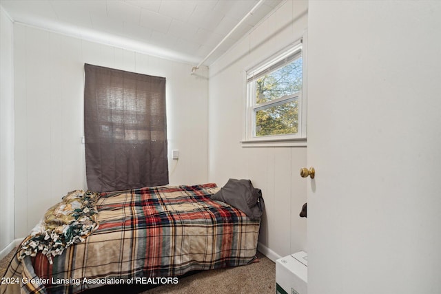 carpeted bedroom with wooden walls