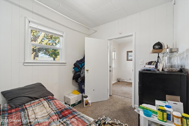 carpeted bedroom with wood walls