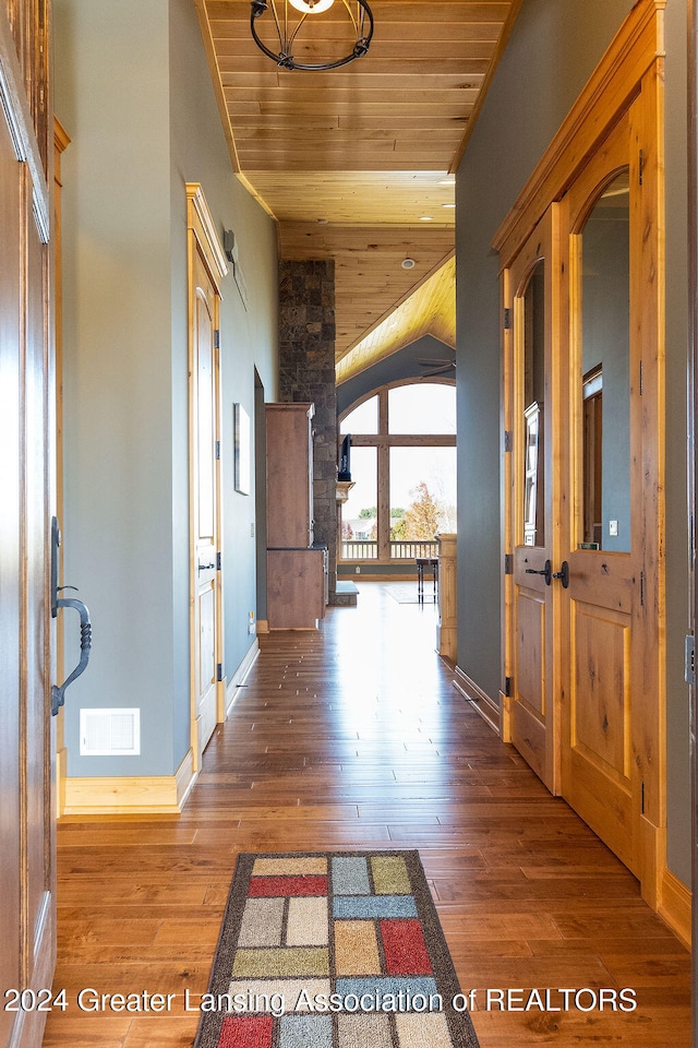 hall with lofted ceiling, hardwood / wood-style floors, and wood ceiling