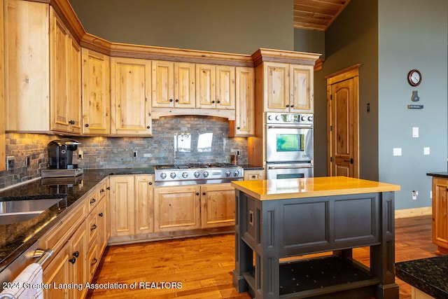 kitchen featuring a kitchen island, appliances with stainless steel finishes, decorative backsplash, and light wood-type flooring