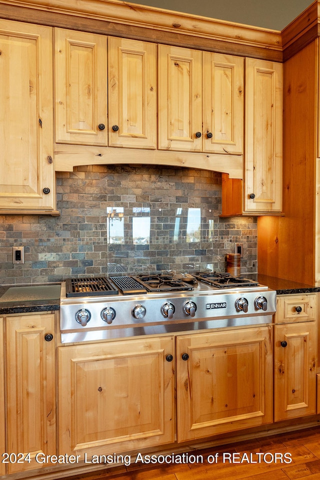 kitchen featuring dark stone countertops, stainless steel gas cooktop, decorative backsplash, and dark hardwood / wood-style flooring