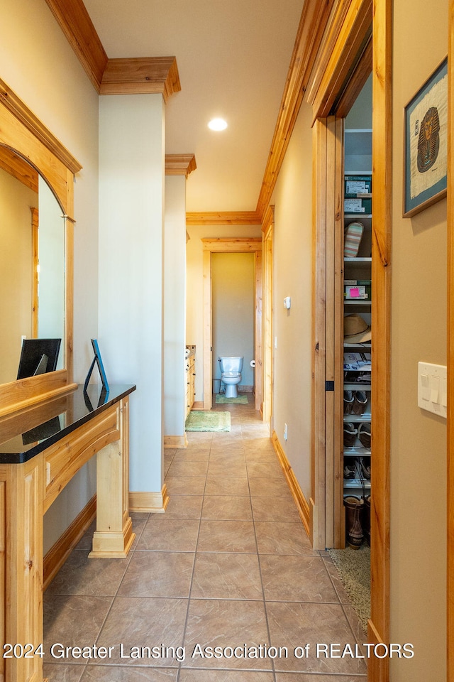 corridor with crown molding and light tile patterned flooring