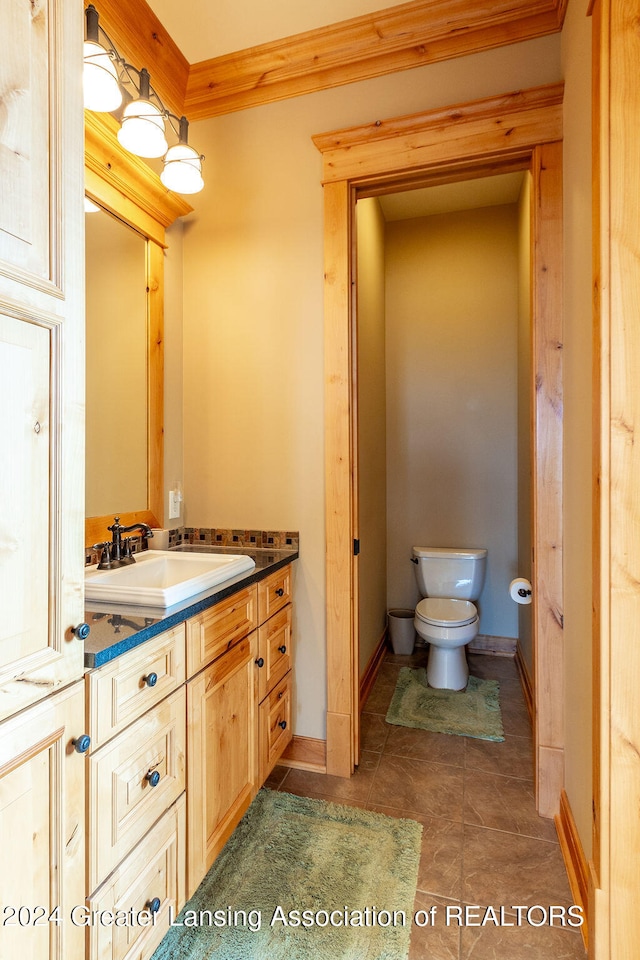 bathroom with vanity, toilet, crown molding, and tile patterned flooring