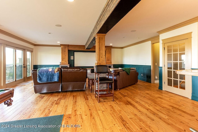 living room featuring ornate columns, ornamental molding, and light wood-type flooring