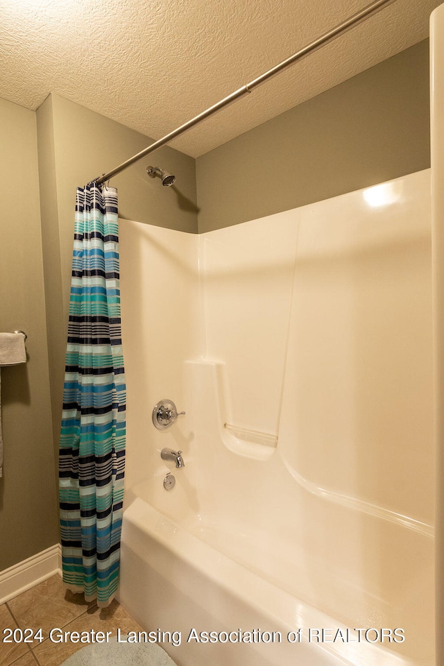 bathroom featuring a textured ceiling, tile patterned flooring, and shower / bathtub combination with curtain