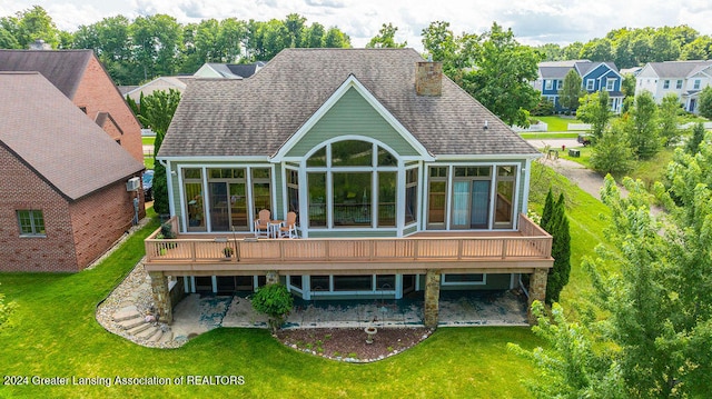 rear view of property with a patio area, a deck, a lawn, and a sunroom