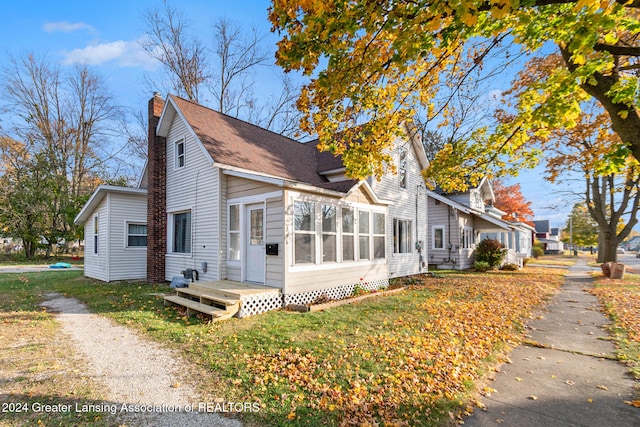 view of side of property featuring a lawn and a sunroom