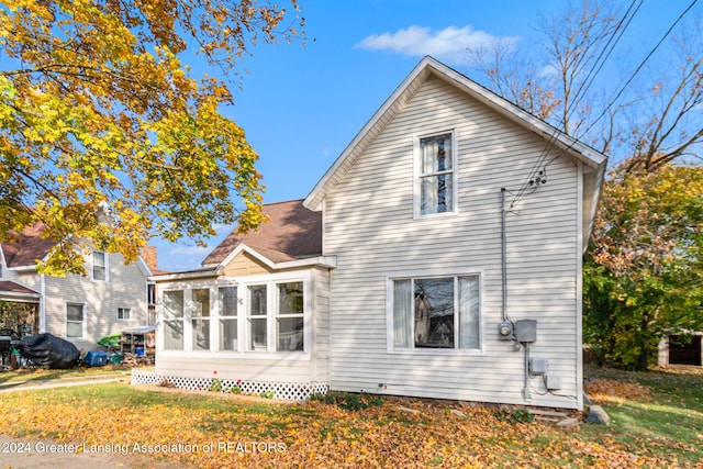 back of house featuring a lawn and a sunroom