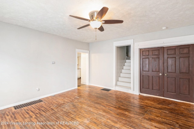 empty room with a textured ceiling, hardwood / wood-style flooring, and ceiling fan