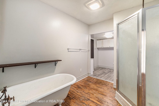 bathroom with hardwood / wood-style flooring and independent shower and bath