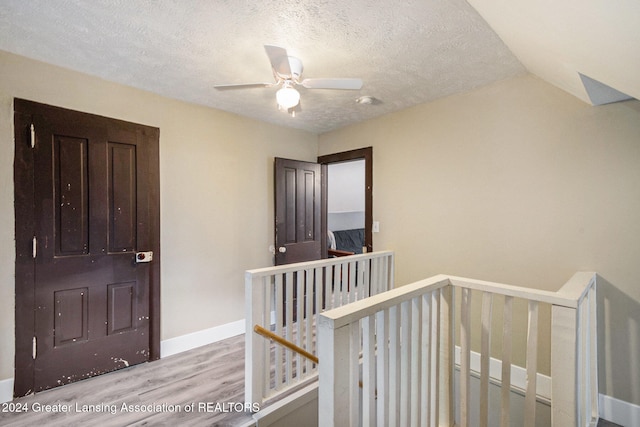 entryway featuring ceiling fan, a textured ceiling, vaulted ceiling, and light wood-type flooring