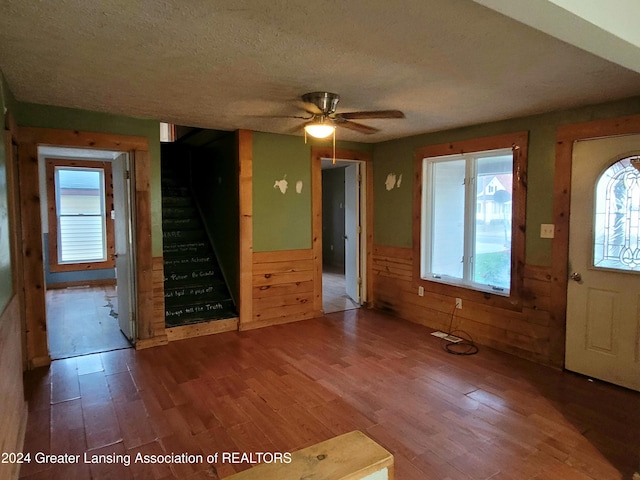 foyer with wooden walls, hardwood / wood-style flooring, a textured ceiling, and ceiling fan