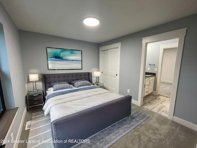 bedroom featuring ensuite bathroom, a closet, and light carpet