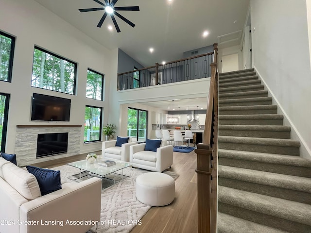 living room with a high ceiling, hardwood / wood-style flooring, ceiling fan, and a healthy amount of sunlight