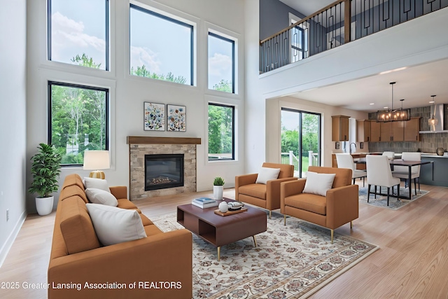 6119 Fresno Ln, East Lansing, MI 48823 - living room featuring a towering ceiling, light wood-style floors, a glass covered fireplace, and a chandelier