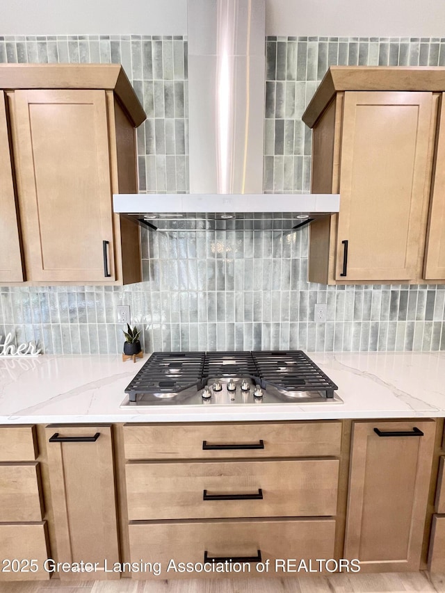 6119 Fresno Ln, East Lansing, MI 48823 - kitchen featuring wall chimney exhaust hood, decorative backsplash, light brown cabinets, stainless steel gas stovetop, and light stone counters