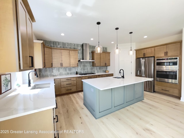 6119 Fresno Ln, East Lansing, MI 48823 - kitchen featuring appliances with stainless steel finishes, wall chimney range hood, backsplash, light wood-type flooring, and a center island with sink