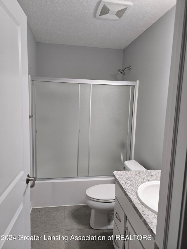 full bathroom with vanity, a textured ceiling, bath / shower combo with glass door, and toilet