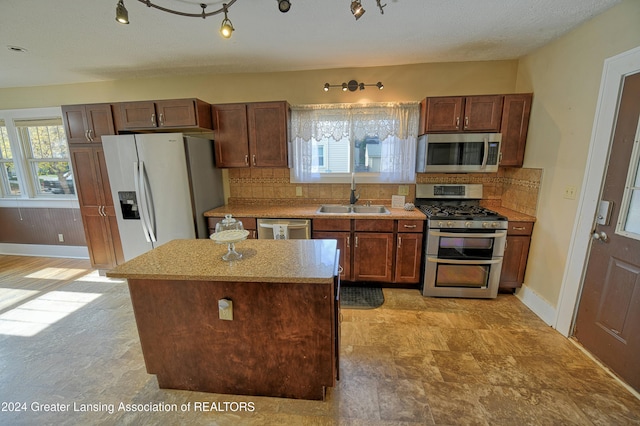 520 W St, Lansing, MI 48915 - kitchen featuring appliances with stainless steel finishes, a sink, tasteful backsplash, a kitchen island, and baseboards