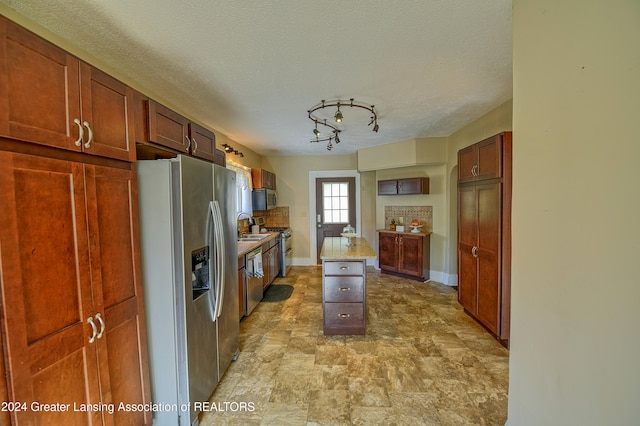 kitchen featuring stainless steel appliances, a textured ceiling, and a center island