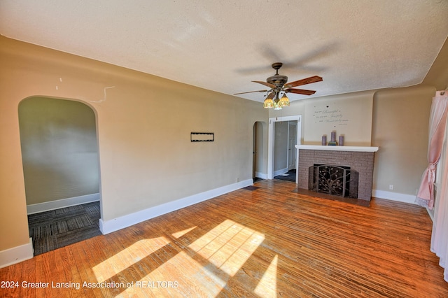 520 W St, Lansing, MI 48915 - unfurnished living room with arched walkways, a ceiling fan, wood finished floors, a textured ceiling, and a fireplace