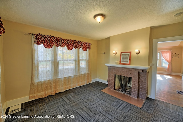 520 W St, Lansing, MI 48915 - unfurnished living room featuring baseboards, a brick fireplace, and a textured ceiling