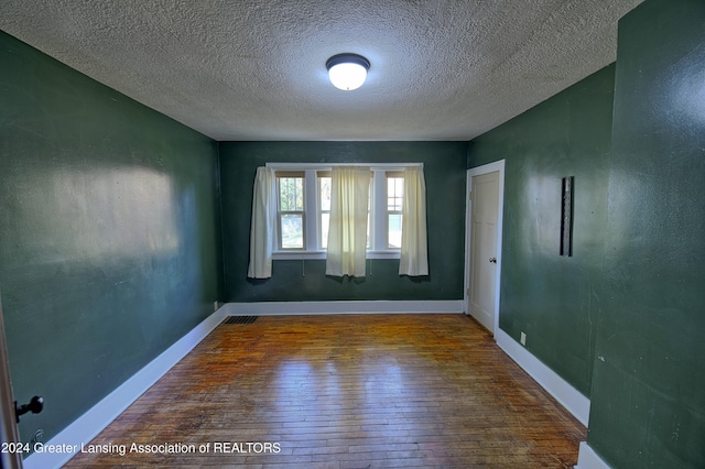 empty room with a textured ceiling and dark hardwood / wood-style flooring