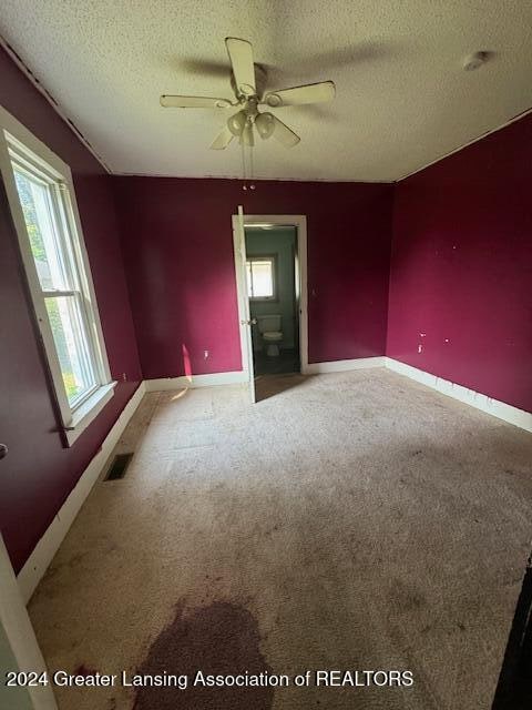 carpeted spare room with ceiling fan and a textured ceiling