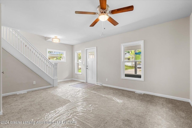 interior space with ceiling fan, a wealth of natural light, and light colored carpet