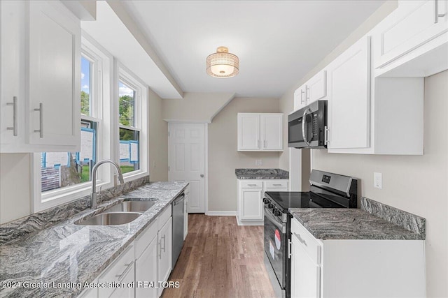 kitchen with white cabinetry, sink, appliances with stainless steel finishes, dark hardwood / wood-style floors, and stone counters