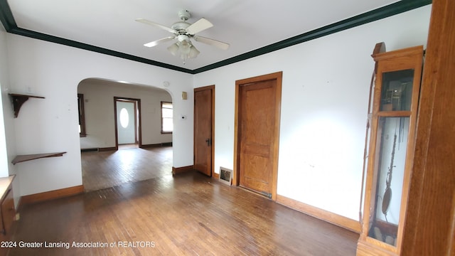 empty room with crown molding, wood-type flooring, and ceiling fan