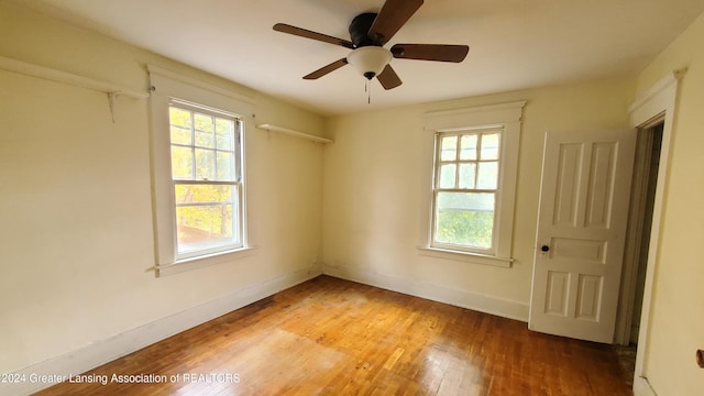 unfurnished room featuring wood-type flooring, a wealth of natural light, and ceiling fan