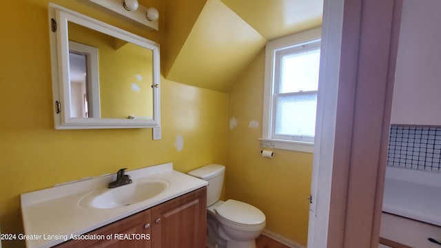 bathroom featuring vanity, a wealth of natural light, lofted ceiling, and toilet