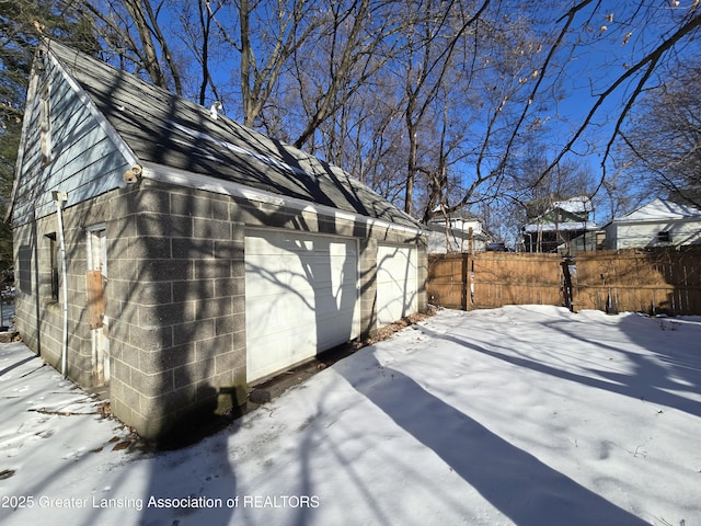 view of snow covered exterior featuring a garage and an outdoor structure