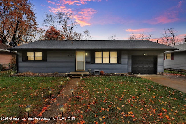 ranch-style home featuring a garage and a lawn