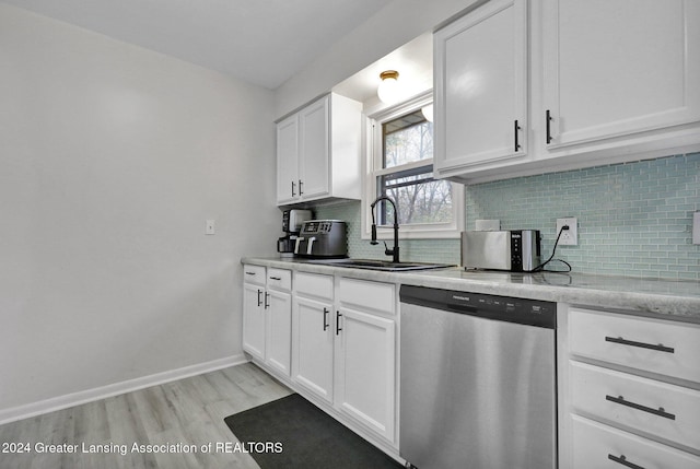 kitchen with white cabinetry, sink, stainless steel dishwasher, light hardwood / wood-style flooring, and decorative backsplash