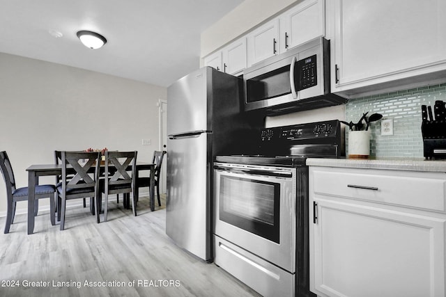 kitchen with white cabinets, light wood-type flooring, stainless steel appliances, and tasteful backsplash