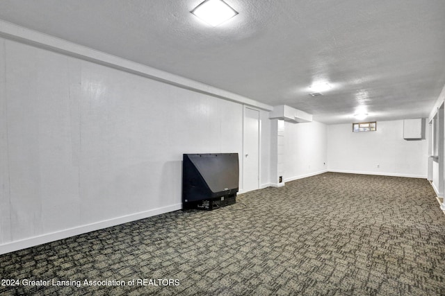 basement featuring a textured ceiling and dark carpet