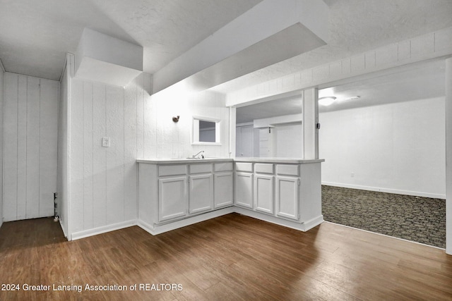 interior space featuring white cabinets, wood walls, and hardwood / wood-style floors