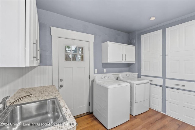 washroom with cabinets, washer and dryer, sink, and light hardwood / wood-style flooring