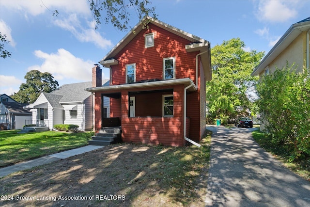 front facade featuring covered porch and a front yard