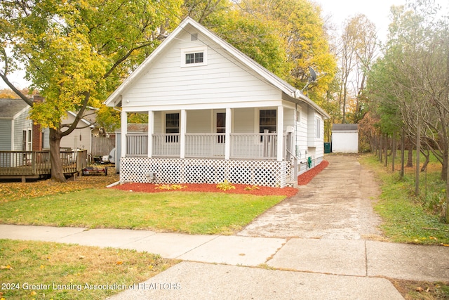 view of front of house with a garage, an outdoor structure, a front yard, and a porch