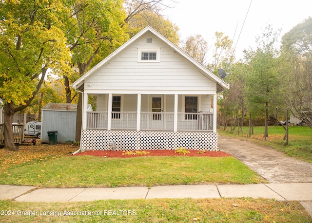 bungalow-style home featuring a front lawn, a shed, and covered porch