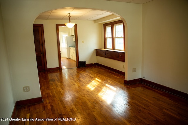 empty room featuring a drop ceiling and dark hardwood / wood-style floors