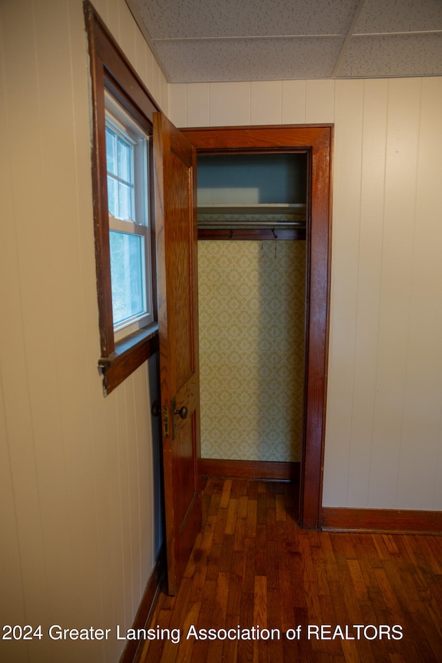 hallway featuring a drop ceiling and dark wood-type flooring