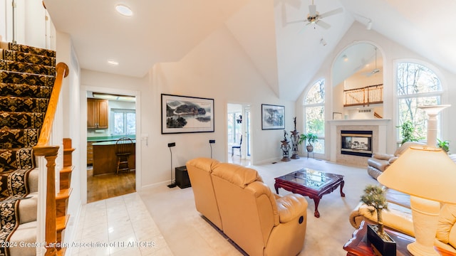 living room featuring high vaulted ceiling, ceiling fan, and a tile fireplace