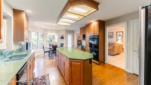 kitchen featuring sink, black appliances, light hardwood / wood-style floors, and a center island