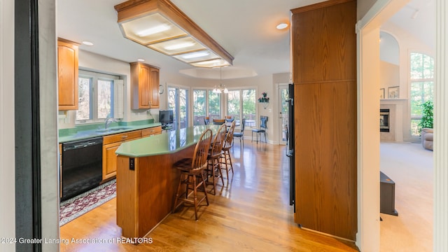 kitchen featuring a center island, a kitchen bar, black dishwasher, light hardwood / wood-style floors, and sink